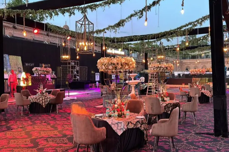 View of outdoor dining and celebration setup at The Earth, Amritsar, illuminated with warm lighting and elegant floral arrangements.